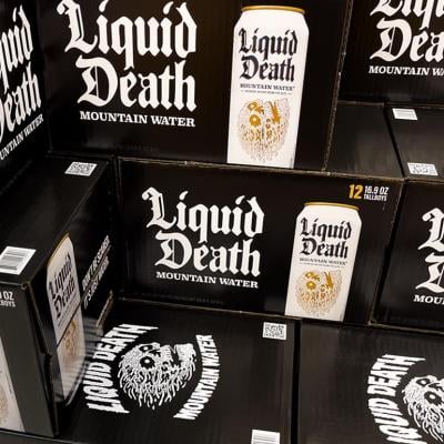 Black boxes of Liquid Death canned mountain water grocery store display.