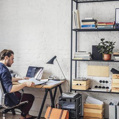View of back of person sitting at a desk in white office chair in modern office with white walls.