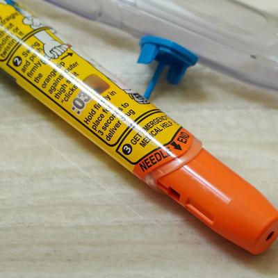 A discarded Epipen auto injector lying beside a sink.