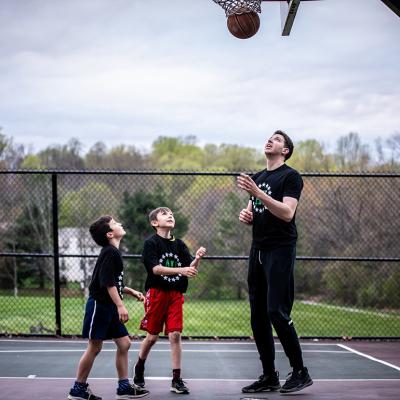 A private sports coach in a basketball session with two young boys.