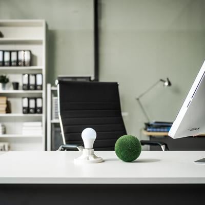 A modern empty office with a vacant chair behind a desk with a computer monitor and desktop decor.