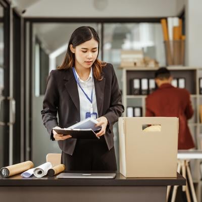 Young businesswoman preparing her work items to put in a box after being laid off.