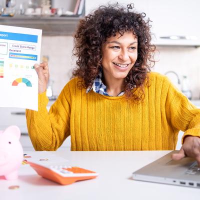 A woman happily holding up a good credit score report.