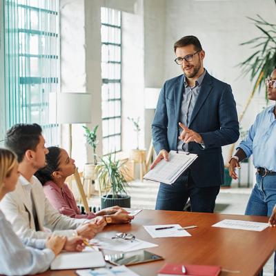 Five members of a diverse business team in a meeting in an office.