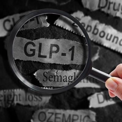 A magnifying glass over a ripped out piece of newspaper headline writing "GLP-1".