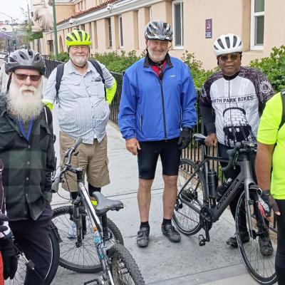 A group of participants in full biking gear posing for a photograph with their bicycles.