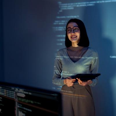 A learning & development employee standing in front of a screen where software lessons are projected.