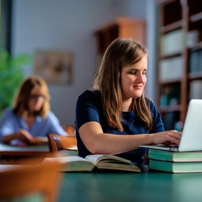 A visually impaired young woman studying in a university library.