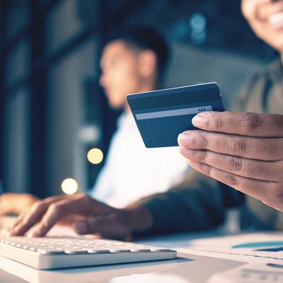 An employee holding a credit card while making an online purchase in the office.