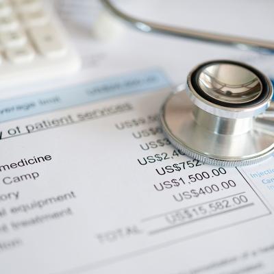 Stethoscope on top of medical expenses bill.