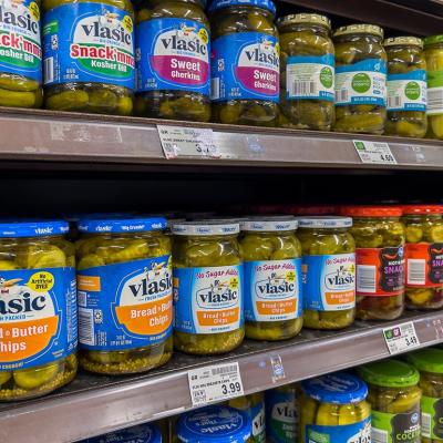  Close up of three shelves of jars of pickles starting with vlasic brand for sale in a grocery store. 