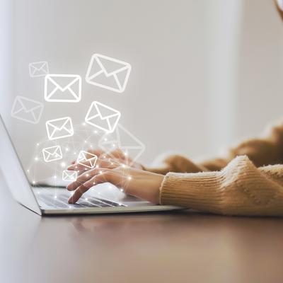 A marketing professional working on her laptop illustrated with graphics of email and newsletter.