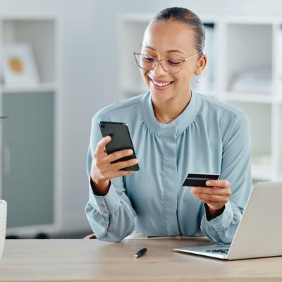 A female business professional using a credit card for an online purchase while working.