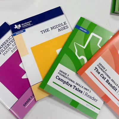 Four Bluebonnet readers in different colors, the new K-5 Texas reading curriculum that includes multiple biblical references.    