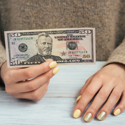 A woman holding a $50 banknote.