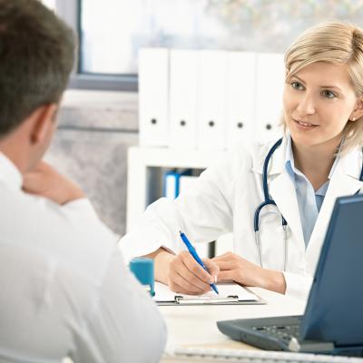 A doctor takes notes while consulting with her patient.