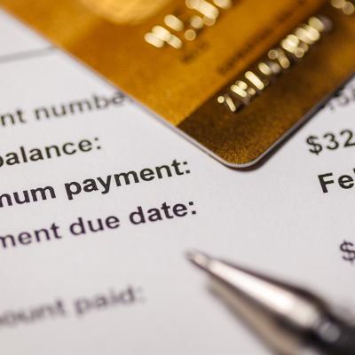 Credit card on top of a bill statement closed up on the minimum amount and due date.