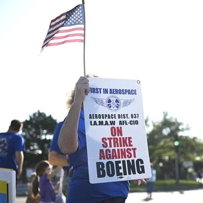 Boeing defense plant workers holding up "Strike Against Boeing" signs outside of a Boeing facility in Berkeley, Missouri.