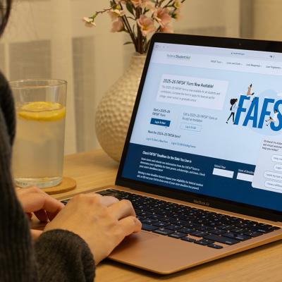 A student browsing the FAFSA website on a laptop.