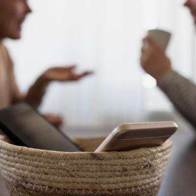 Two phones in a basket with two people catching up in the background.