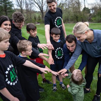 A group of young kinds with their parents form a circle to join hands before a game.