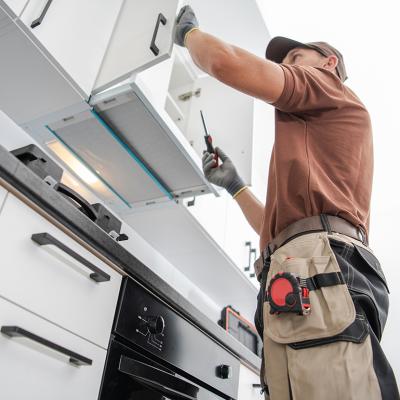 A cabinetmaker finishing a white, modern cabinet installation