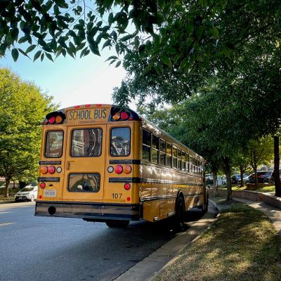A yellow school bus waits by a bus stop in a family neighborhood in Fairfax County, Virginia.