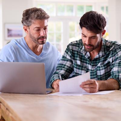 A gay couple at home checking finance documents.