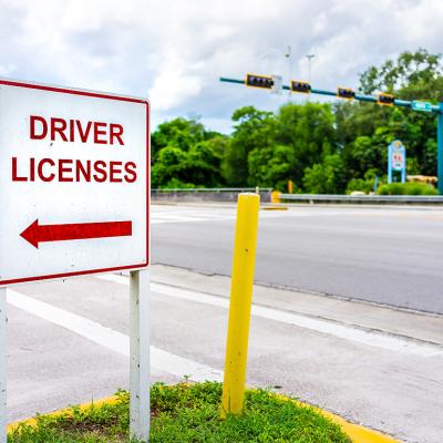 A roadside sign showing direction to a driver's license office.