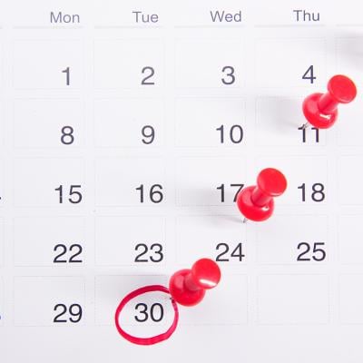 Pushpins on a calendar with an encircled date.