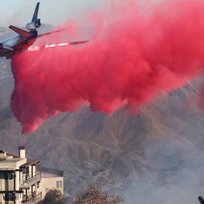 A firefighting aircraft drops the fire retardant Phos-Chek near homes during the Palisades Fire on January 10, 2025 in Topanga, California.