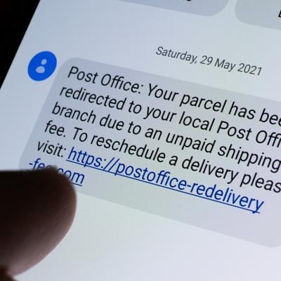 Phone displaying a USPS scam text message with a link.