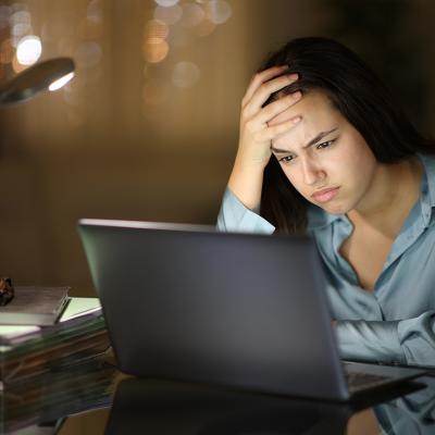 A young female professional frustratingly looks at her laptop at work.