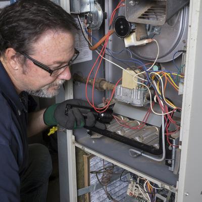 A technician inspects a gas furnace before its cleaning.