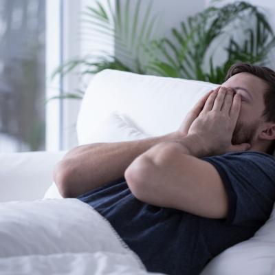 A man on bed struggling to sleep.
