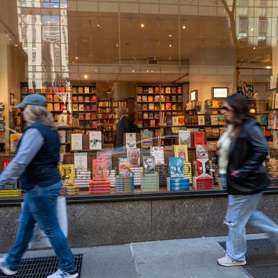 People passing by the glass display of a book store in Manhattan, New York.