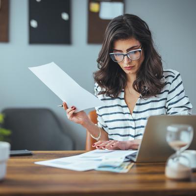 A businesswoman reading finance documents in an office.