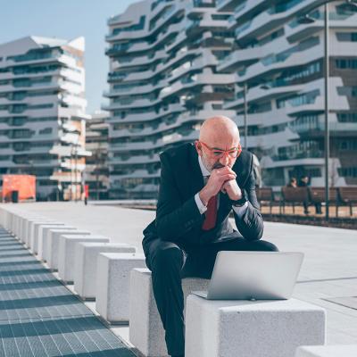 Businessman sitting outdoors and concentrates on his laptop.