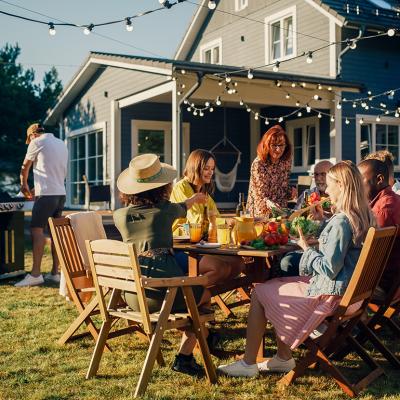 Family and friends dining outside a home during a barbecue dinner party.