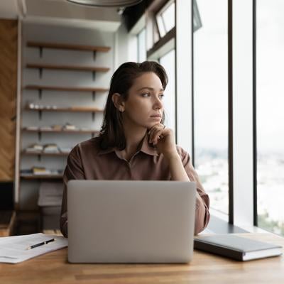 A young businesswoman in an office looking out the window.