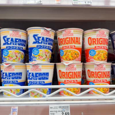 Assorted Cup Noodles packages on a grocery store shelf.