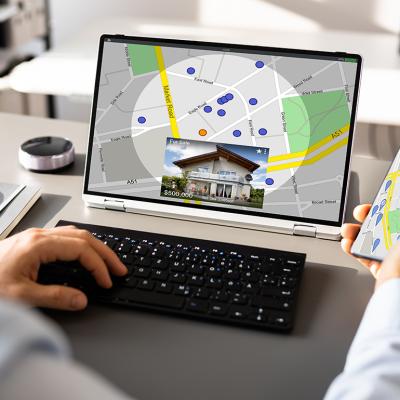 Person looking up a map view of a property's location using a laptop and a phone.