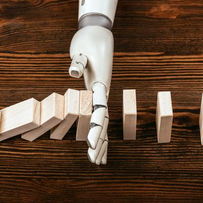 A robotic hand prevents wooden domino blocks from falling midway.
