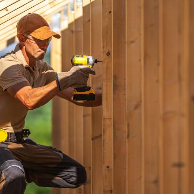 A skilled carpenter securing wooden panels using an electric power drill.