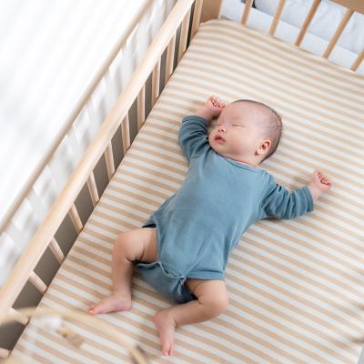 An infant quietly sleeps in a crib.