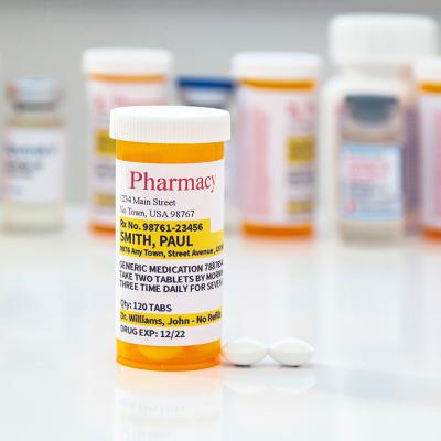 A generic prescription medicine pill bottle in front of a row of other pill bottles.