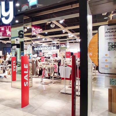 A clothing store having a sale in a shopping mall with a QR code system displayed at the entrance.