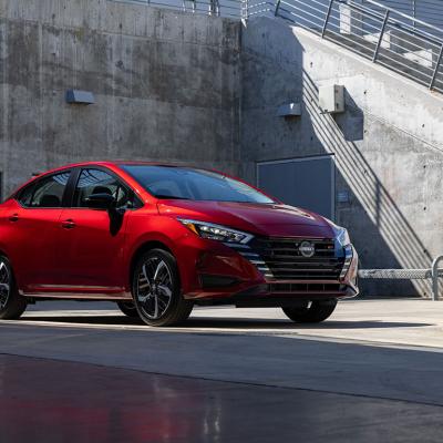 A red 2025 Nissan Versa parked in a concrete lot.