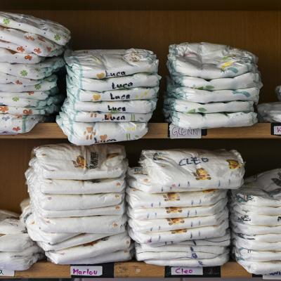 A daycare center's shelf with stacks of various children's diapers with their names written on them.