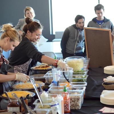 A catering team preparing food in front of awaiting employees.
